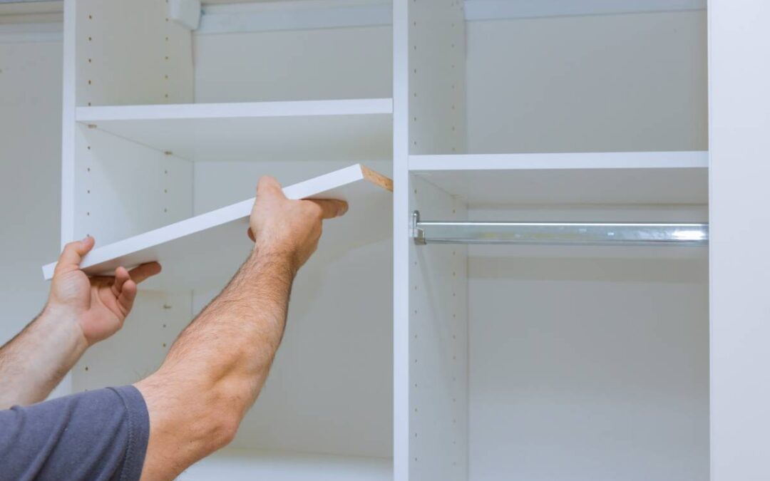 A storage pro professional installing white wooden shelves into a bedroom closet organization system