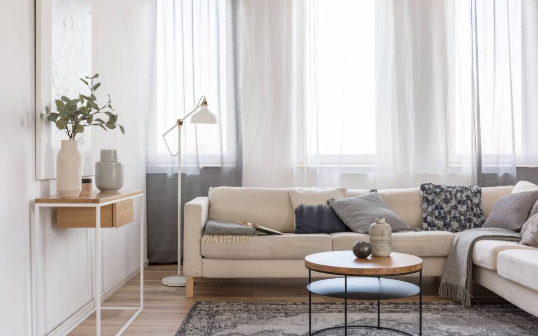 A round coffee table paired with an L-shaped sectional in a neutral color palette living room at Marksons Furniture & Windows near Grand Cayman Islands